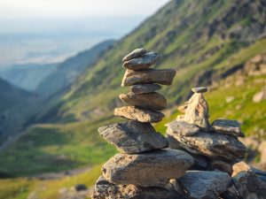 Stone stack with balanced stones on blurred mountain background in sunset warm light